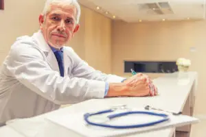 man in a labcoat sitting behind a desk. He is a doctor. 